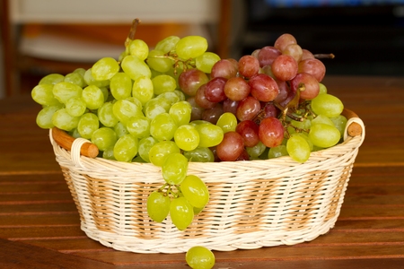Green and red grapes in the wicker basket.の写真素材