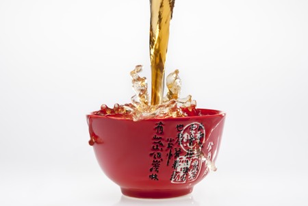 Pouring tea into red teacup with splashesの写真素材