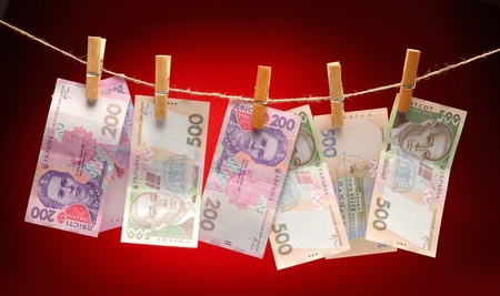 Ukrainian grivnas Hanging on Rope with Clothespins on red backgroundの写真素材