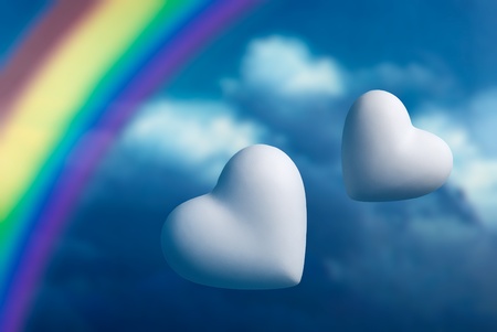 Rainbow and two hearts against a blue sky backgroundの写真素材