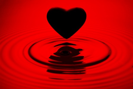 Black heart siluett over red water ripples backgroundの写真素材