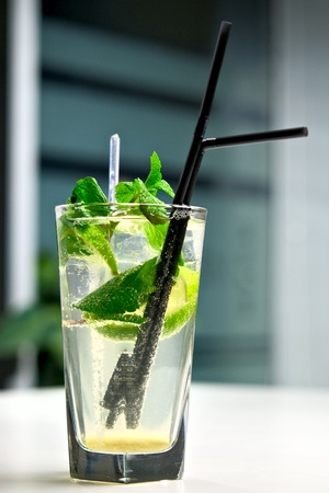 Glass of cool mojito cocktail on a white table with a background of interior cafeの写真素材