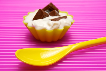 Empty yellow spoon with portion of whipped cream and chocolate over pink background. Shallow DOFの写真素材