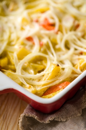 Close-up of baked in oven potatoes with onion served in the white casseroleの写真素材