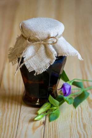 Canvas and flower decorated rustic jam pot with walnut jam standing on wooden tableの写真素材