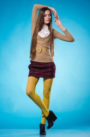 Beautiful teen girl with long straight hair, posing on blue backgroundの写真素材