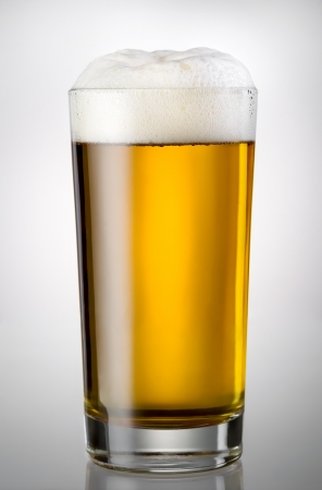Glass full of beer and foam isolated on a gradient gray backgroundの写真素材