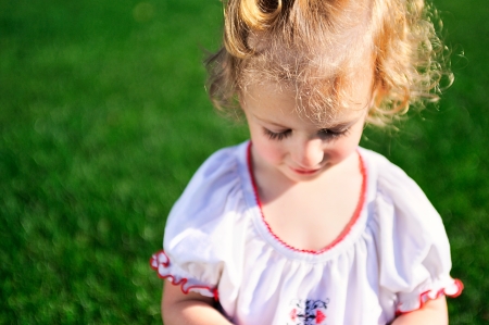 Portrait of beautiful baby girl on the lawn in summer parkの写真素材