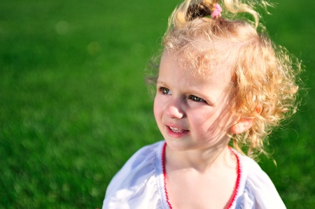 Portrait of beautiful baby girl on the lawn in summer parkの写真素材