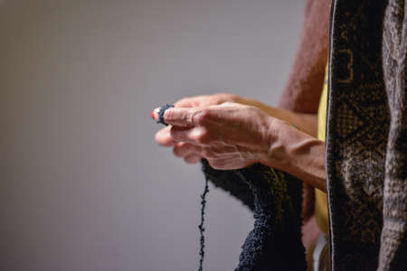Close-up of a woman's hands knitting on a gray background