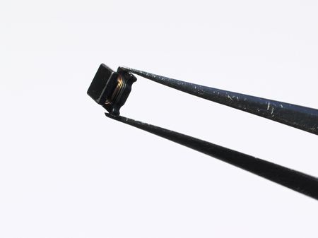 The chip inductance kept by a tweezers on a white background.の写真素材