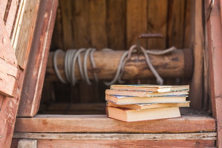 A stack of vintage books lie on a wooden old well. The concept of education, science
