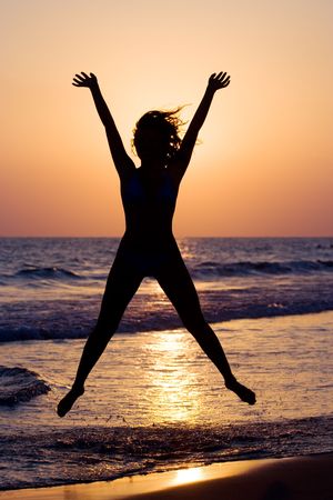A silhouette of a happy woman jumpingの写真素材