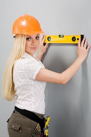 Photo of the builder-woman, measuring level of an inclination of a wall