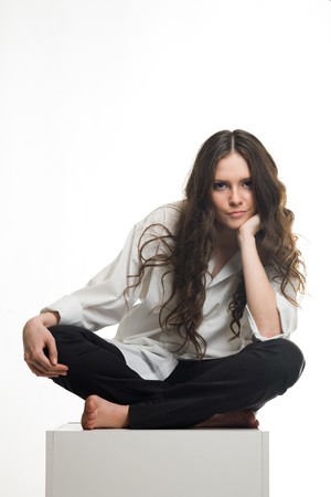 Photo of the girl sitting on a cube on a white backgroundの写真素材