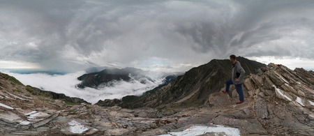 A man stands in the mountains and looks into the distance, panoramaの写真素材