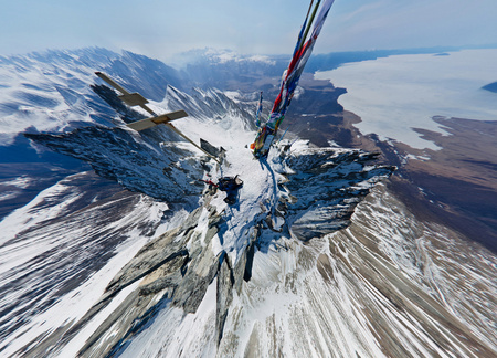Stretched wide-angle view of the top of aerial photography snowy mountains on a sunny day.の写真素材