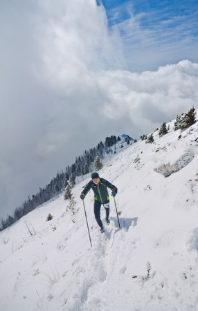 Arshan, Russia - 04.2015: young man skyrunning running with walking sticks in hands during a ÑÑ snow mountain marathon.のeditorial素材