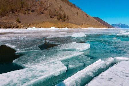 Clumps of blue ice floating in the water in a crack near the shore. Lake Baikal.