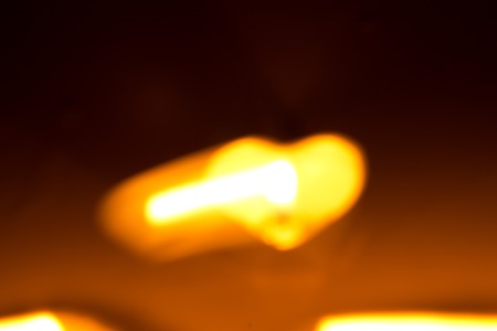 Small round candle with heart-shaped tablet is lit in the dark.の写真素材