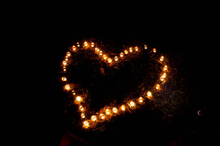 Heart shape of burning candles on the ground.の写真素材