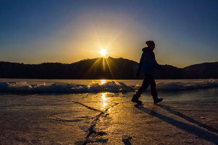 Girl is on the ice of Lake Baikal in the light of the setting sun.の写真素材