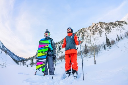 Freeriders male skiers and snowboarders are in the mountains in the snow.