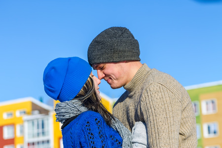 Young couple hugging and kissing background colored housesの写真素材