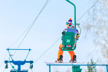 Snowboarder rises to the chairlift to the trackの写真素材