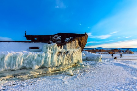 Old rusty ship on ice covered sunset standing on the shore.の写真素材