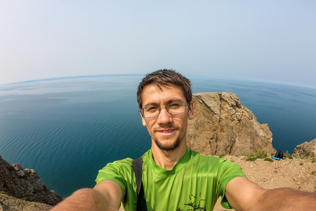 Man makes selfie on the rocks by the sea.