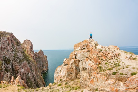 Red-haired girl stands on the edge of a cliff by the sea.の写真素材