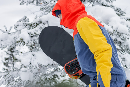 freerider with a snowboard in overalls stands on top of a snowy mountain.の写真素材