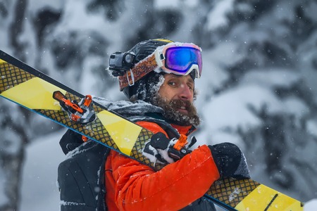 Portrait young man ski goggles holding ski in the mountains.の写真素材