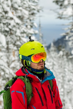 Portrait young man ski goggles holding ski in the mountains.