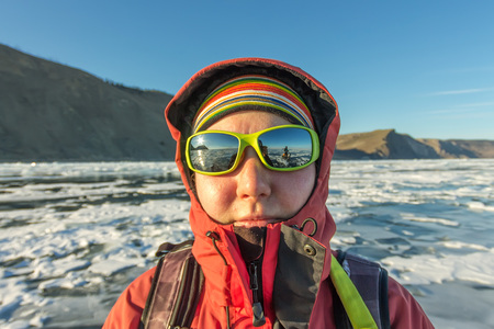 Portrait of a woman in sunglasses on the ice of Lake Baikal.