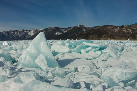 dawn in the blue hummocks of ice lake baikal, in a snowy field in winter on a journey.の写真素材