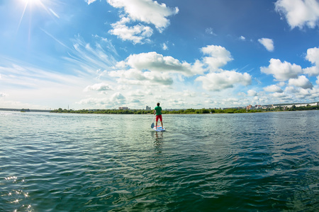 Sup surfing man stand up paddle boarder paddling at sunset on river.の写真素材