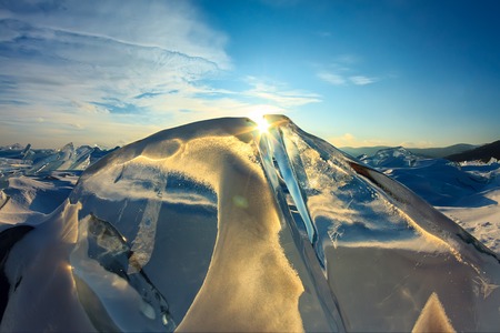 Transparent blue Toros Baikal ice is shining through the crack sunsetの写真素材