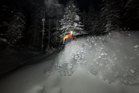 freerider snowboarder jumping at night with a springboard in the forestの写真素材