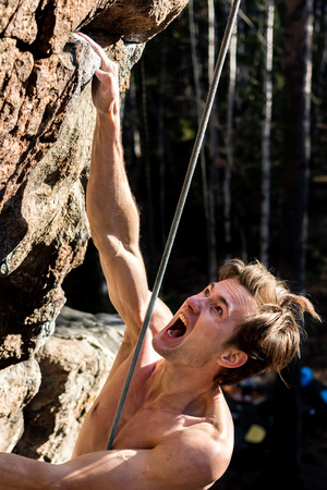 rock-climber man screaming for tension holding on to a rock with one hand, close-upの写真素材