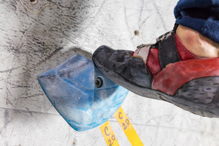 rocky shoe on a big hook stands with the tip of the sock close up, on the climbing wall in the roomの写真素材