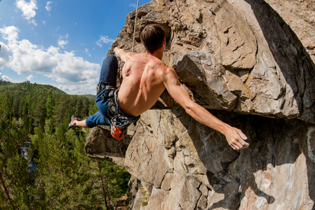 Climber Extreme climbs a rock on a rope with the top insurance, overlooking the forestの写真素材