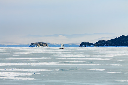 Ice boat rides on the ice of Lake Baikal in the background Olkhon in the winter foggy morning awayの写真素材