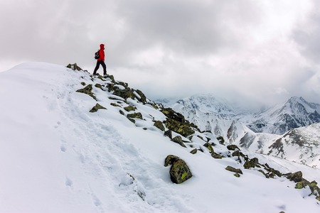 backpacker man high in snowy mountains. Portrait in a red jacket