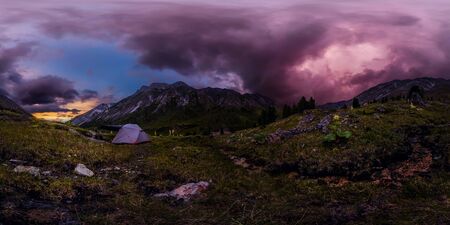 Panorama tent in the mountains on a background of purple clouds at sunsetの写真素材