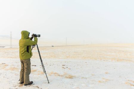 photographer takes pictures with a tripod in winter, yellow landscapes of the island of Olkhon, Baikal, Russiaの写真素材