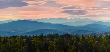Wide angle panorama autumn forest,misty hills mountain tops in pink dawnの写真素材
