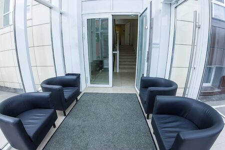 Interior of the medical clinic bright foyer with black chairs.