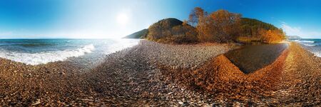 Autumn panorama of a pebble beach by the sea with waves with a bay with leaves at sunset with a blue...